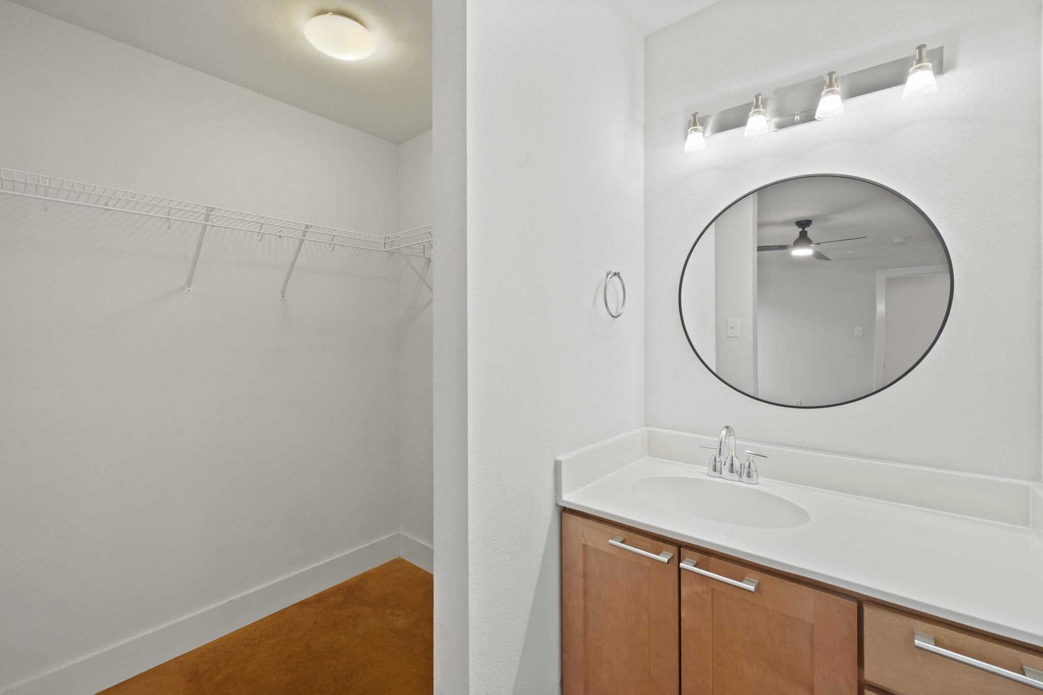 Bathroom vanity beside an empty walk-in closet with wire shelving.