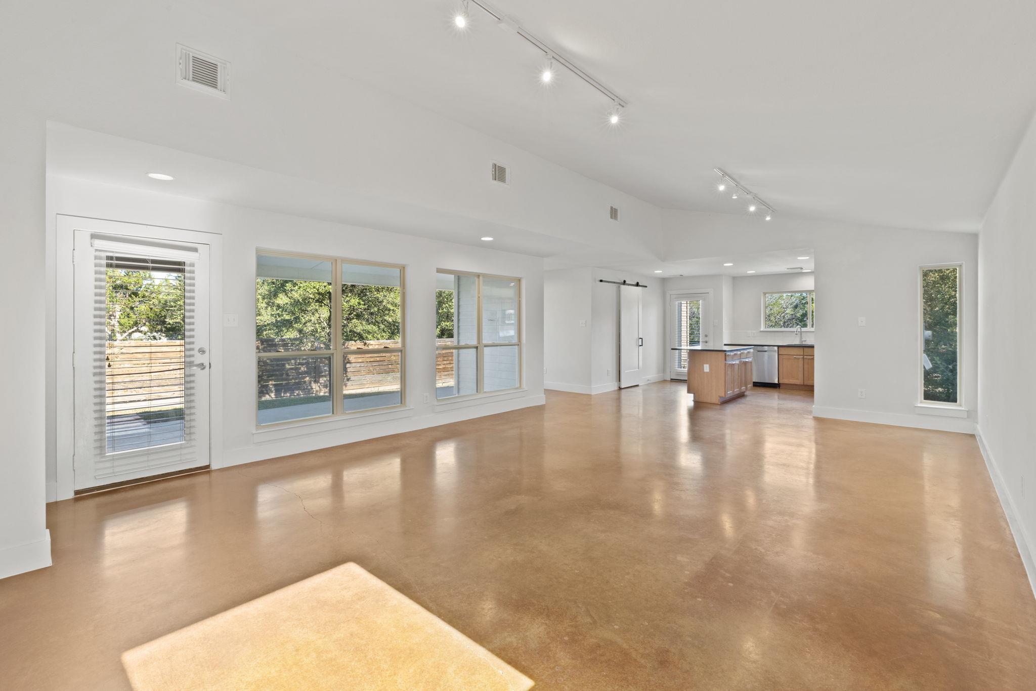 Open-plan living area with polished concrete floors, large windows, and a kitchen island.