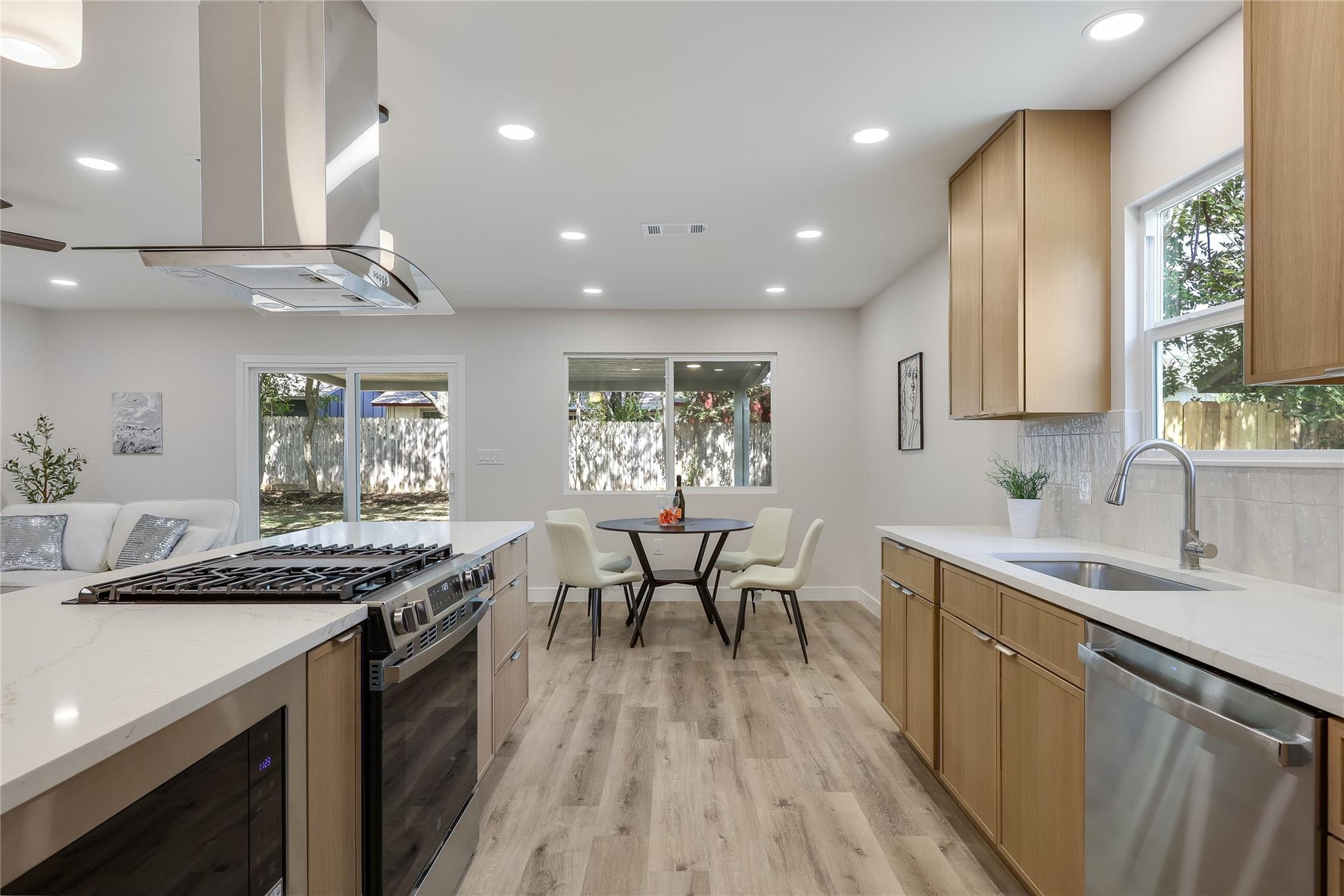 Bright kitchen with light wood cabinetry, a large island range, and a dining nook by the windows.