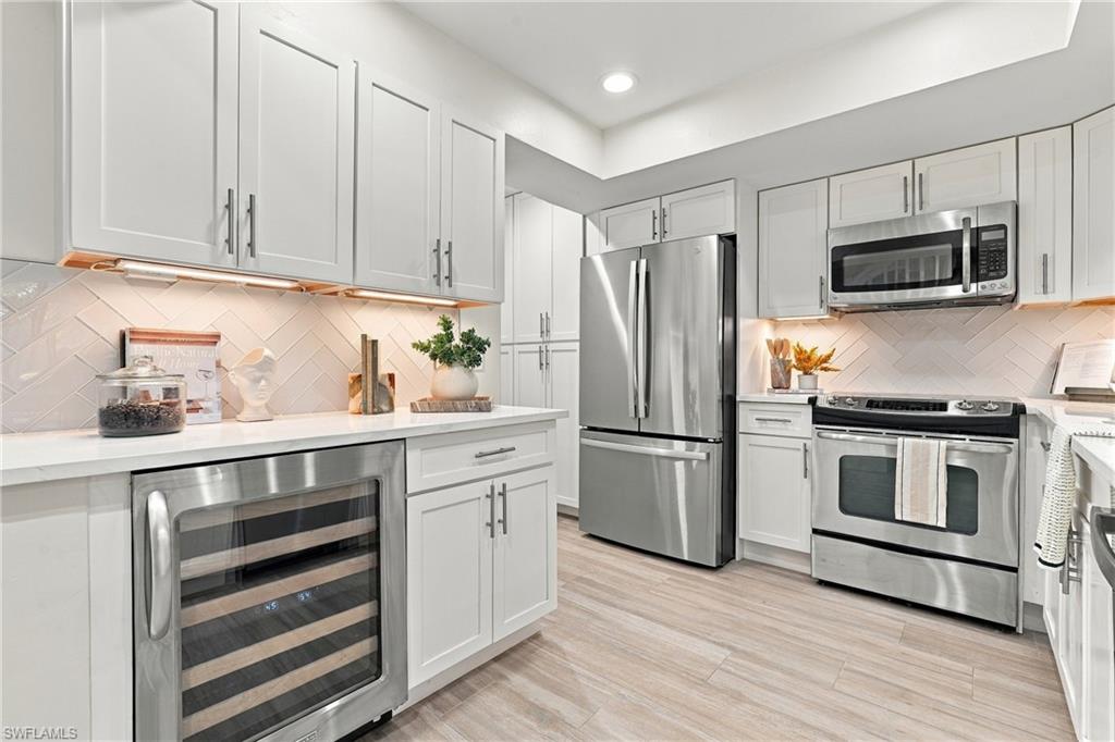 Kitchen with white shaker cabinets, stainless steel appliances, herringbone backsplash, and a built-in wine cooler.