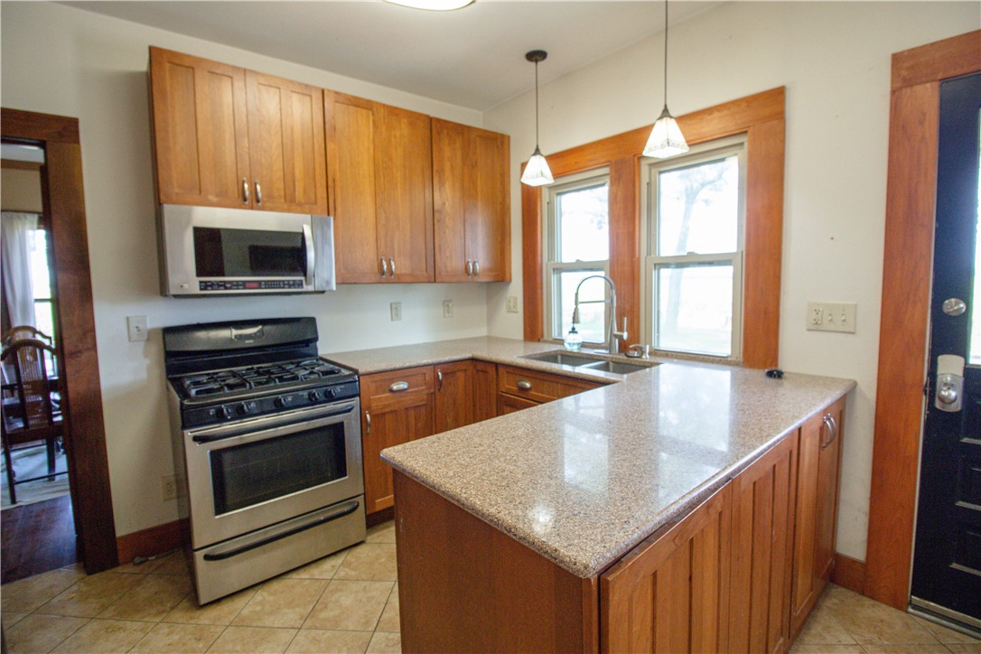 Kitchen with a large granite island, wood cabinets, stainless steel appliances, and a gas range.