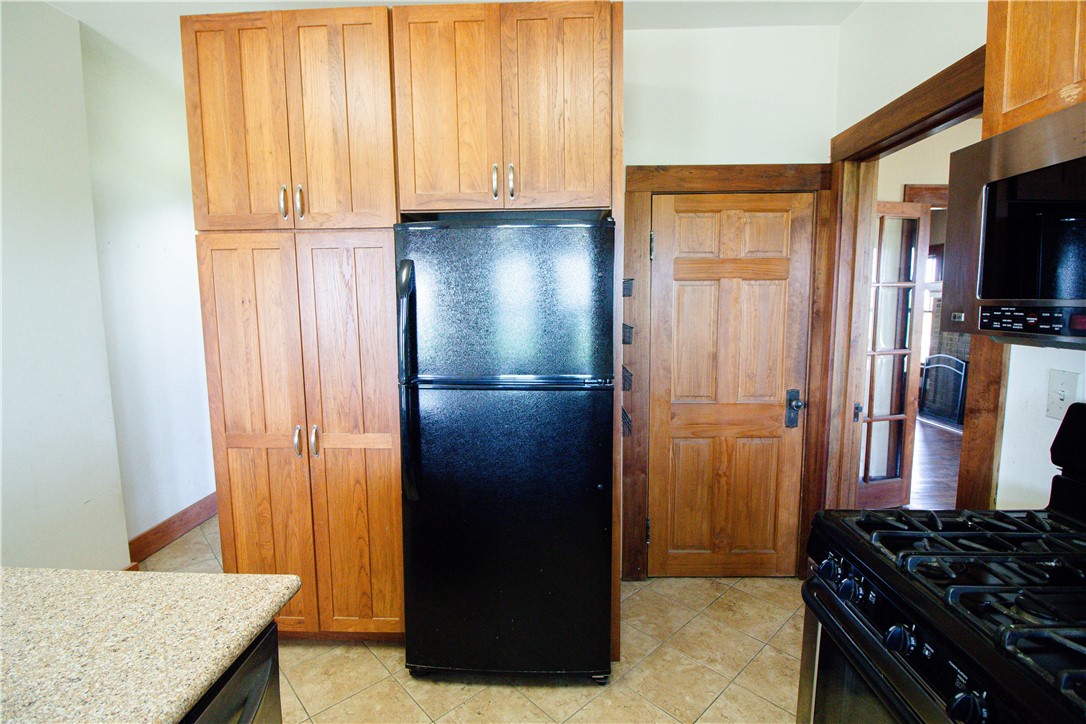 Kitchen with tall wood cabinets, black appliances, and a wood-paneled door.