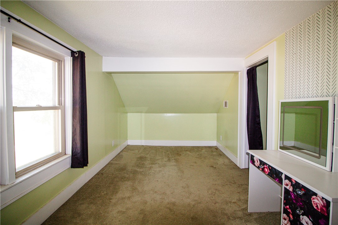 Upstairs room with a sloped ceiling, pale green walls, and a large curtained window.