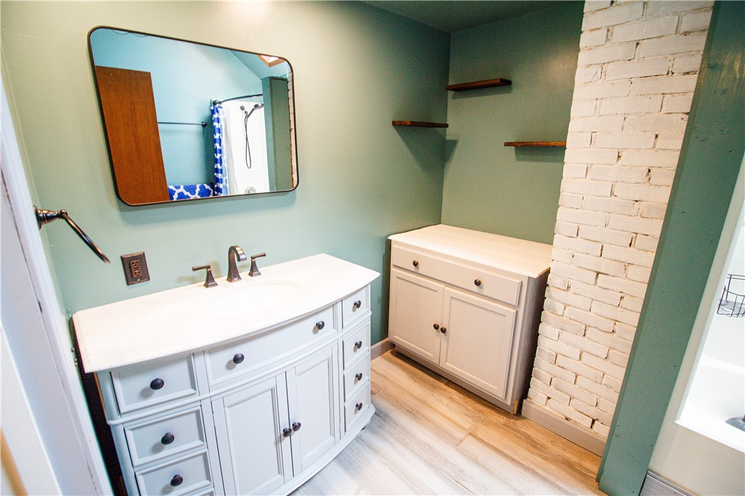 Bathroom with a white vanity, large mirror, and white brick partition.