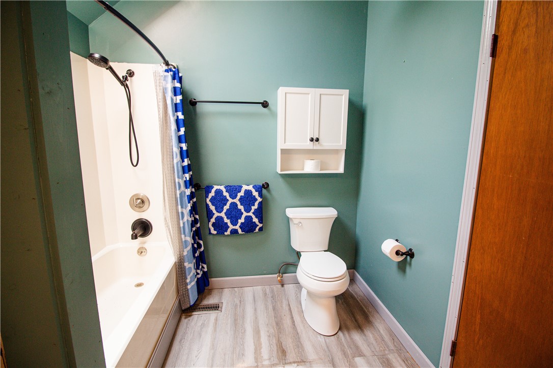 Bathroom with teal walls, a white tub and shower, and a blue patterned curtain and towel.