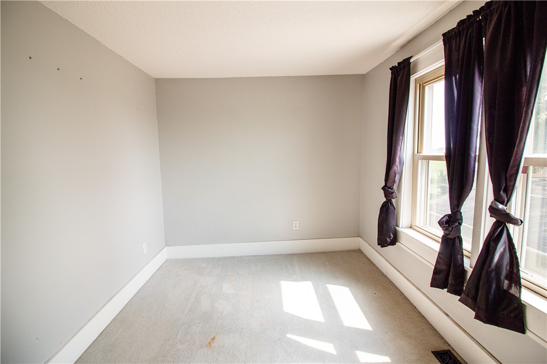 Empty carpeted room with tall windows and dark curtains.