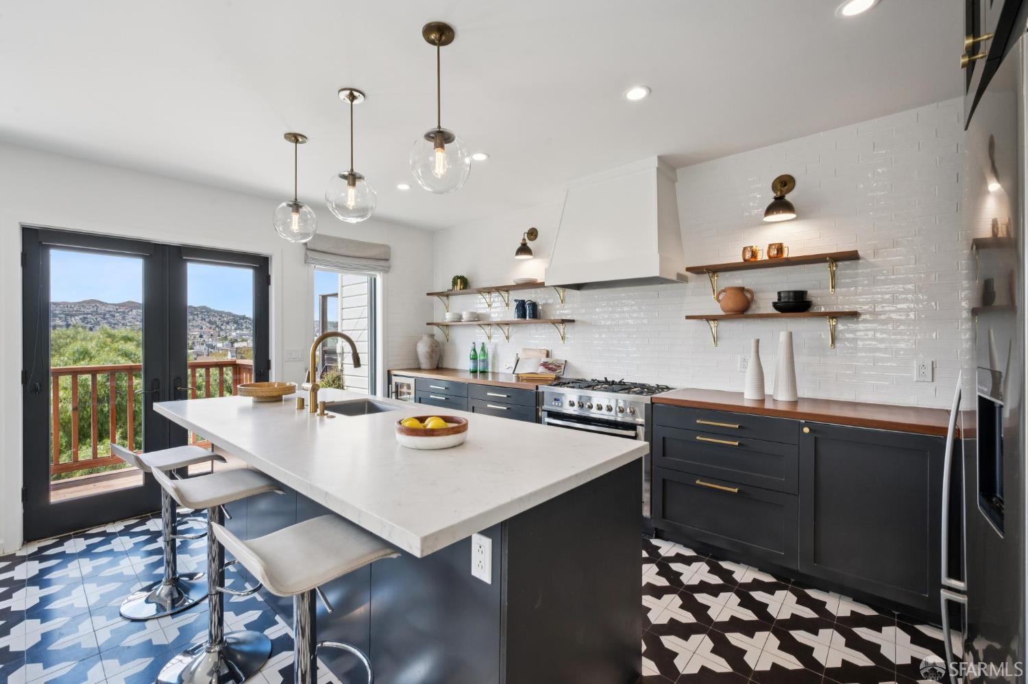Remodeled kitchen with a large white island, navy cabinets, patterned tile floors, and deck doors.