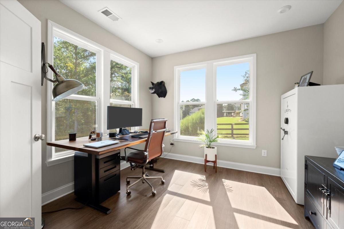 Home office with a wooden desk, large windows, and a white safe.