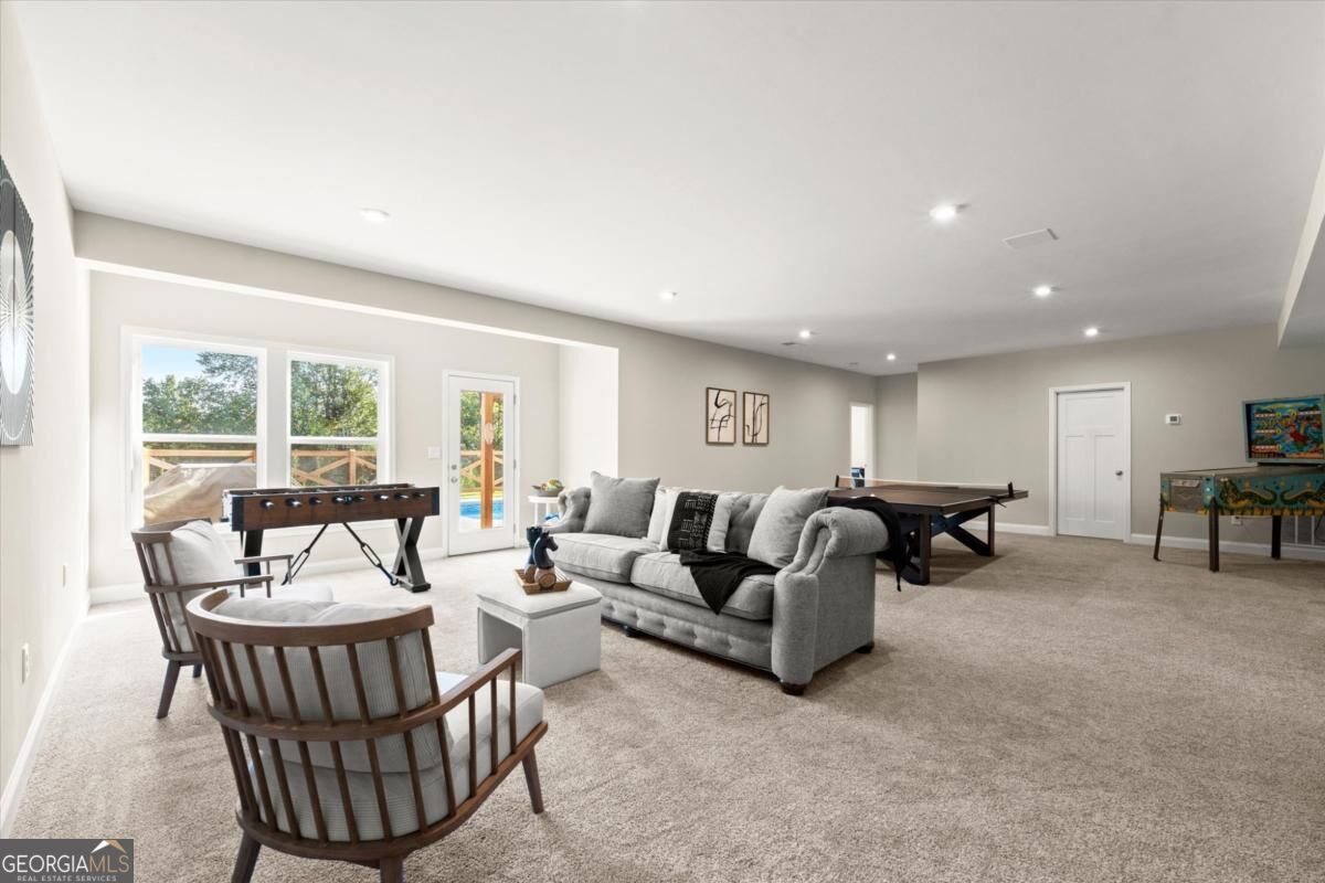 Furnished basement game room with foosball and ping-pong tables, lounge seating, and large windows.