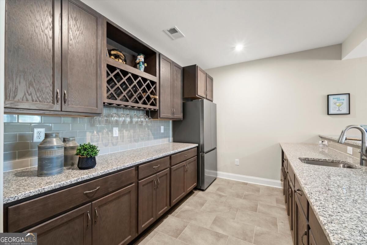 Kitchen with dark wood cabinetry, a built-in wine rack, granite counters, and stainless steel refrigerator.