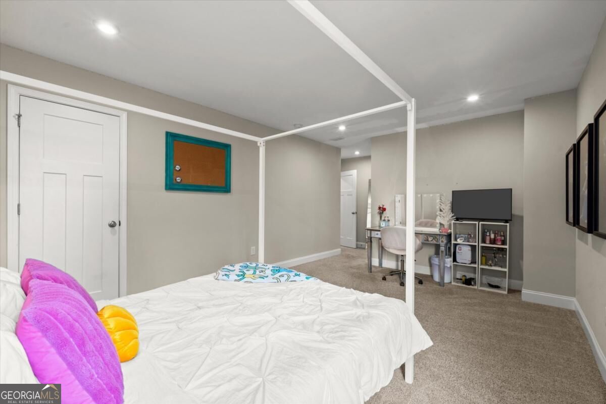 Bedroom with a white canopy bed, colorful pillows, and a vanity and TV area.