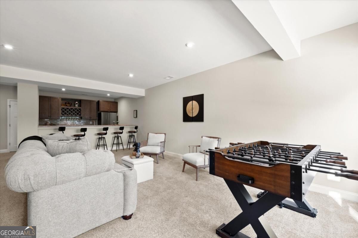 Furnished recreation room with a foosball table, sectional sofa, and bar counter.