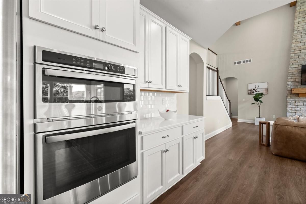 Kitchen with stainless double wall ovens, white cabinetry, and view into the open living area.