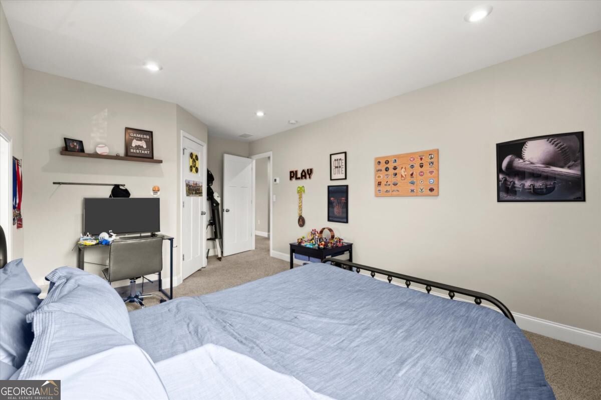 Bedroom with light blue bedding, a television and desk, and gaming and sports memorabilia.