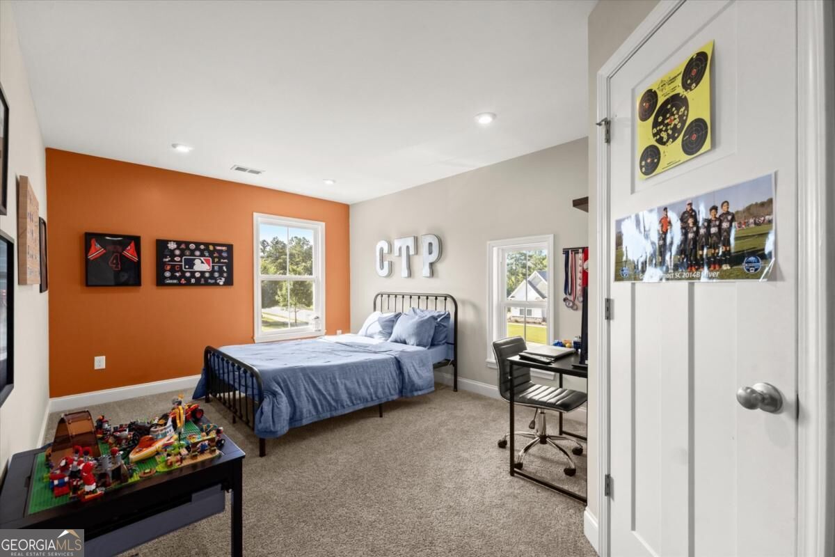 Bedroom with blue bedding, an orange accent wall, a desk, and sports memorabilia.