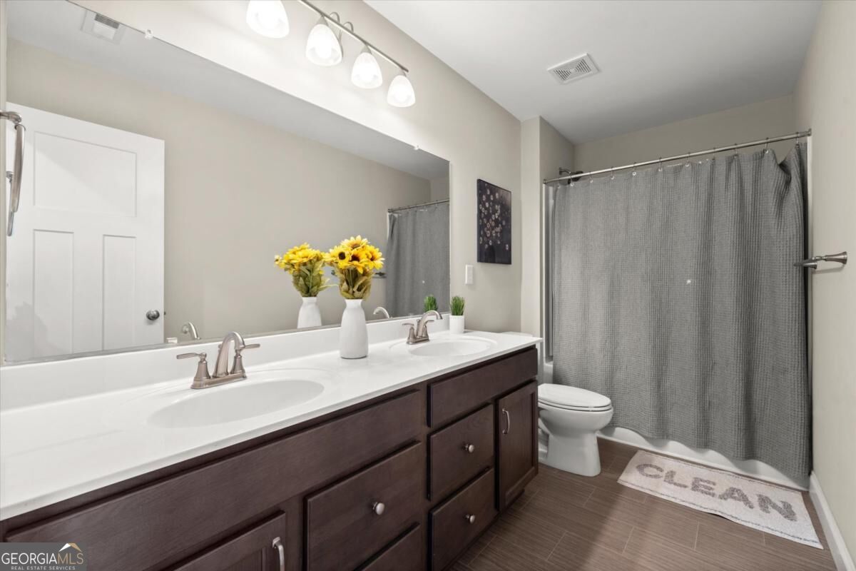 Bathroom with a dark double vanity, white countertop, large mirror, and gray shower curtain.