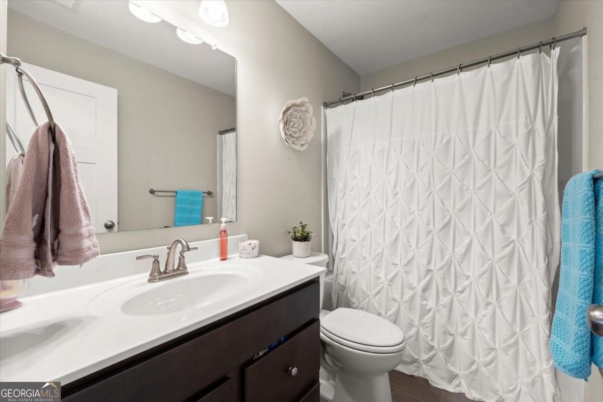 Bathroom with a dark wood vanity, large mirror, and white geometric shower curtain.