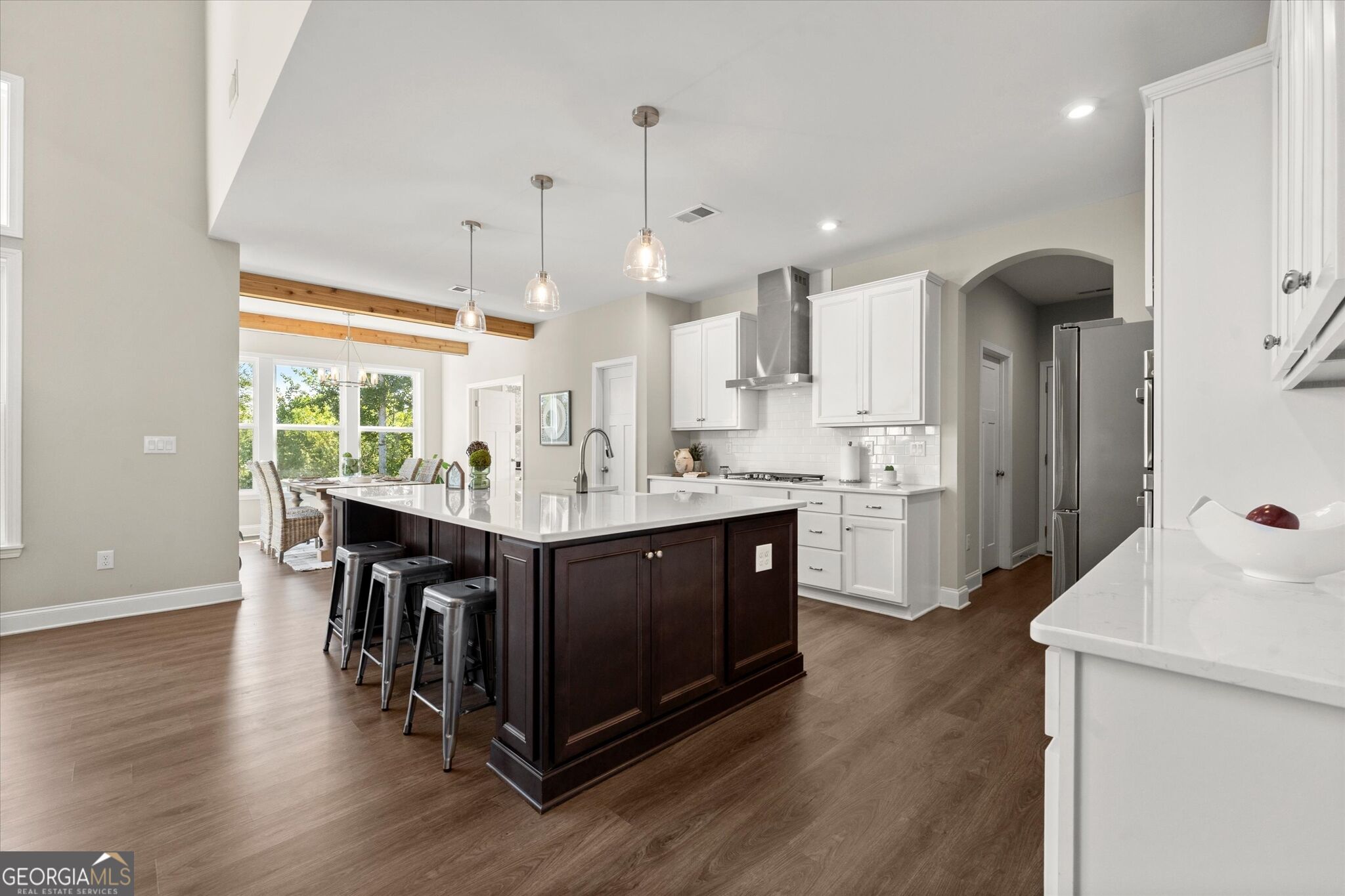 Open kitchen with a dark wood island, white cabinetry, and a dining area by large windows.