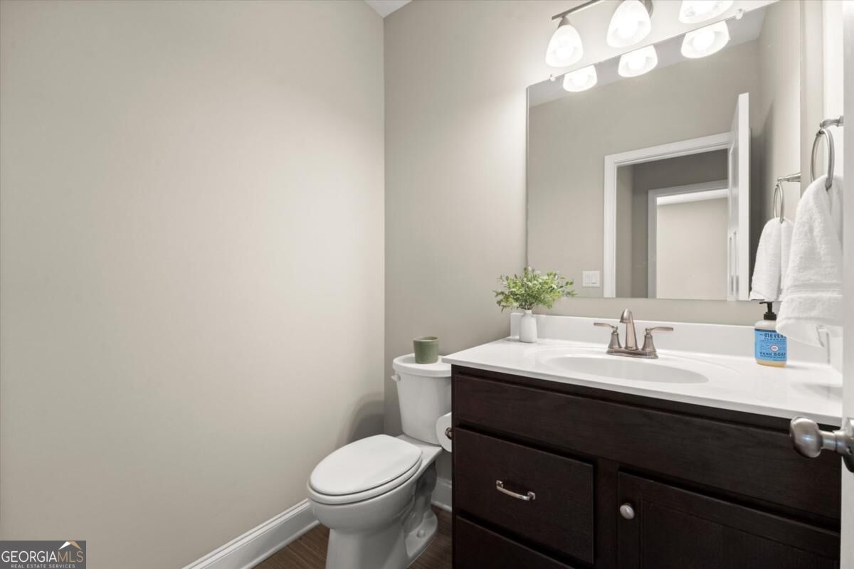 Bathroom with a dark wood vanity, large mirror, and toilet.