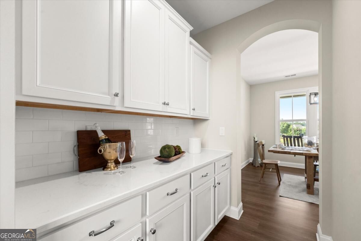 White kitchen with paneled cabinets and subway tile backsplash, opening to a dining area.