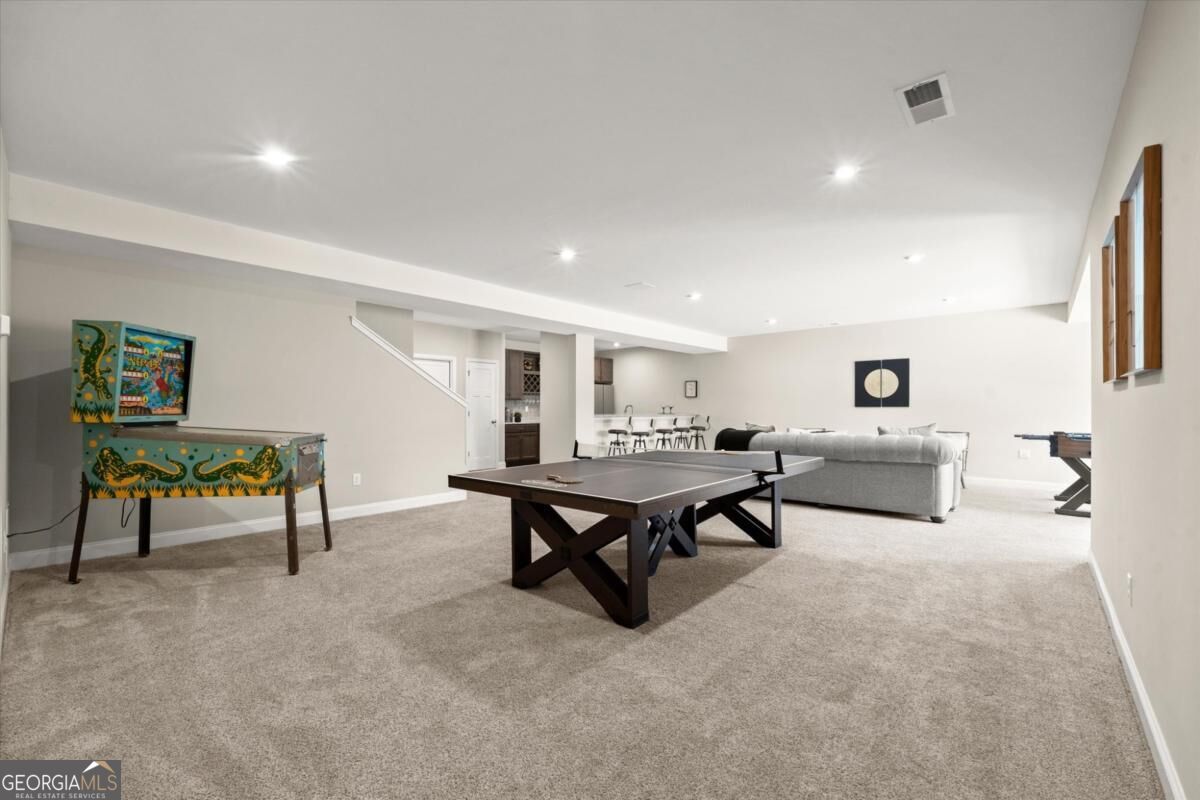 Finished basement recreation room with ping-pong and foosball tables and a gray sectional sofa.