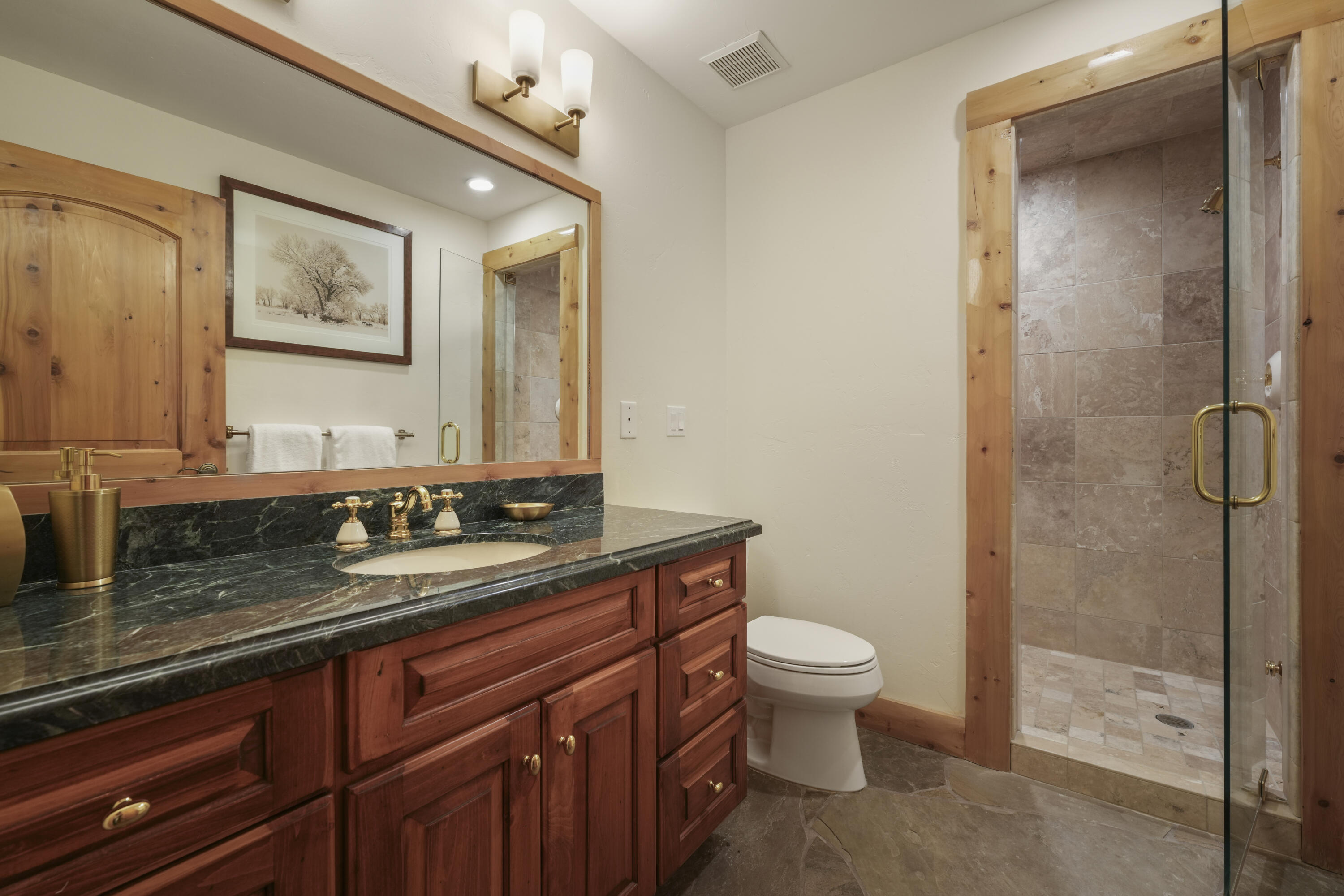 Bathroom with a dark wood vanity and a glass shower framed in natural wood.