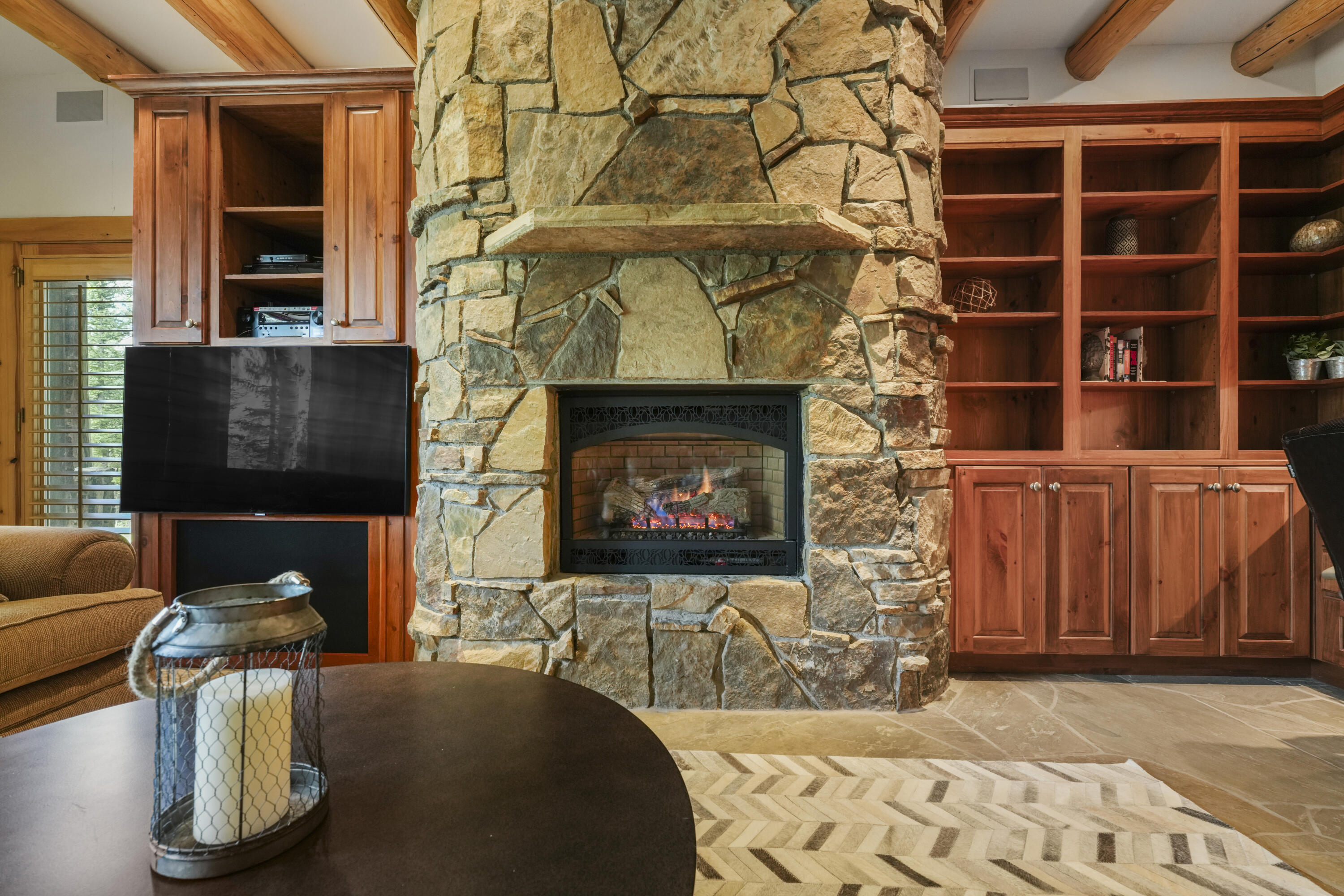 Living room with a floor-to-ceiling stone fireplace, built-in wood cabinets, and a television.