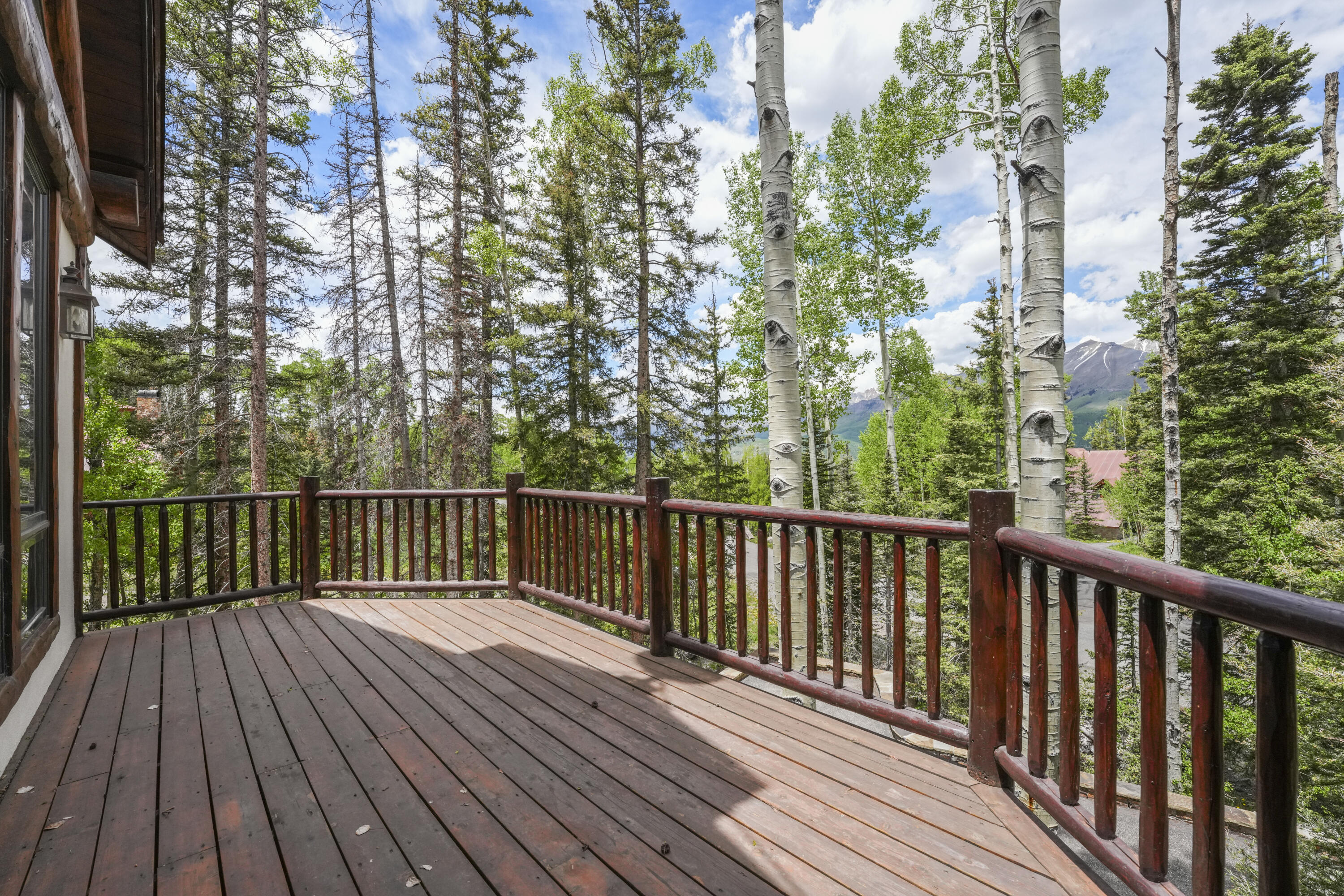 Wooden deck overlooking aspens, evergreens, and distant mountains