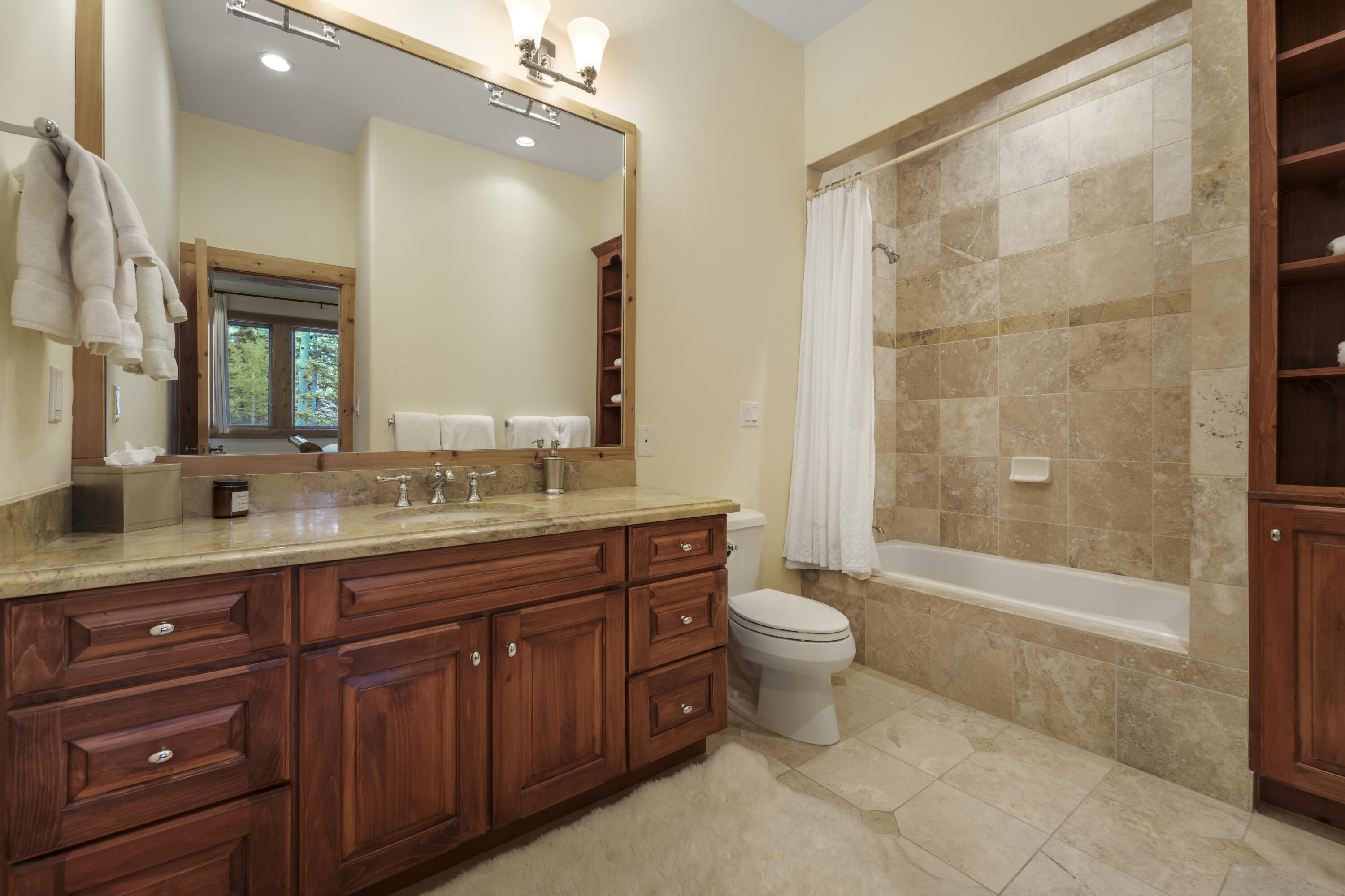 Bathroom with a dark wood vanity and a stone-tiled tub and shower.