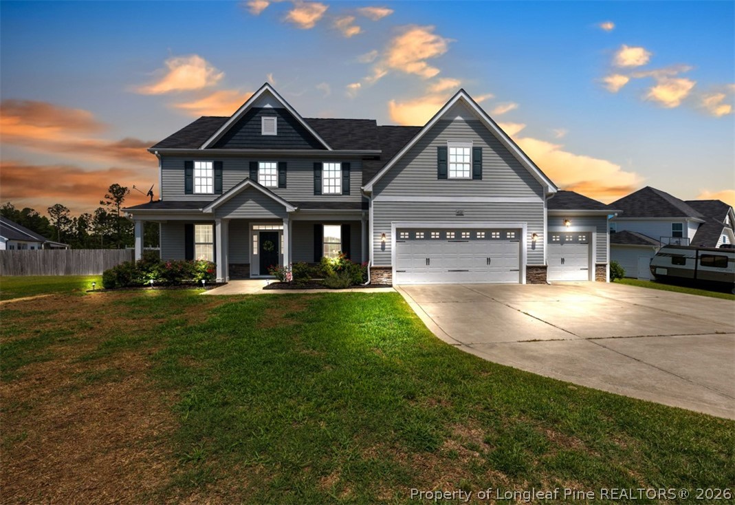 Two-story gray house with multiple gables and a three-car garage at dusk.