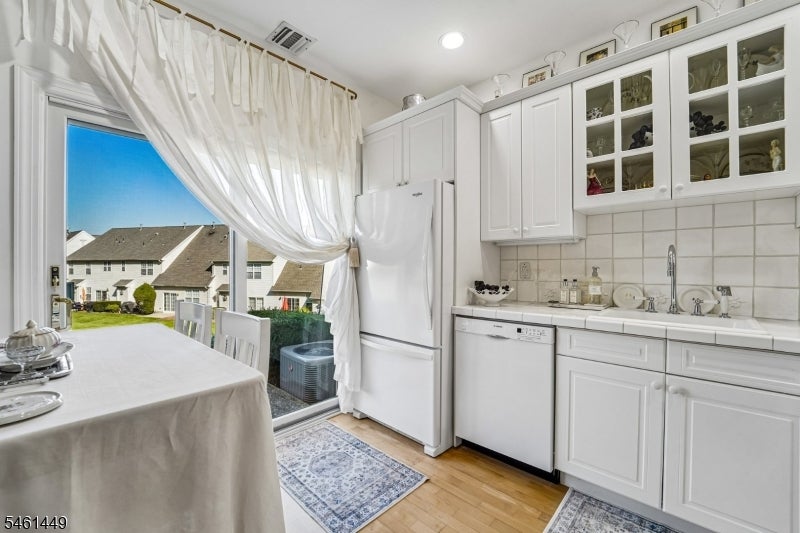 White kitchen with glass-front cabinets and a dining table beside a sliding glass door.