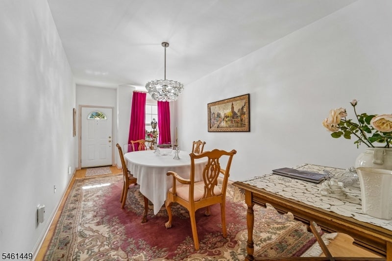 Dining room with a round table, wooden chairs, chandelier, and magenta curtains.