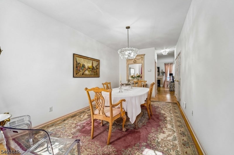 Dining room with carved wooden chairs, a crystal chandelier, and an ornate patterned rug.