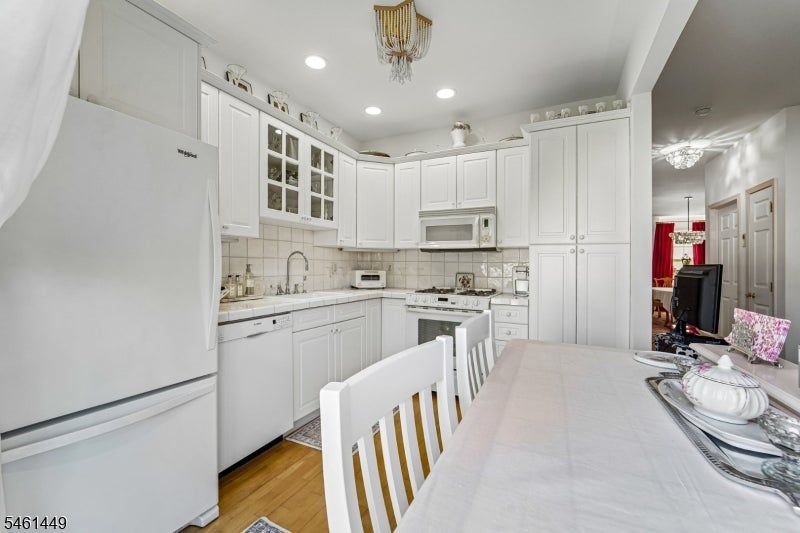 White kitchen with extensive cabinetry, stainless appliances, and a dining table in the foreground.
