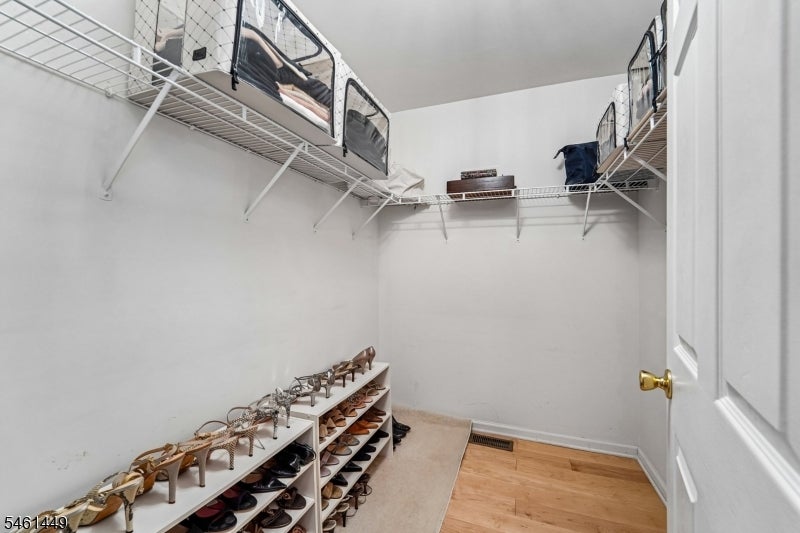 Walk-in closet with wraparound wire shelving and racks filled with shoes.