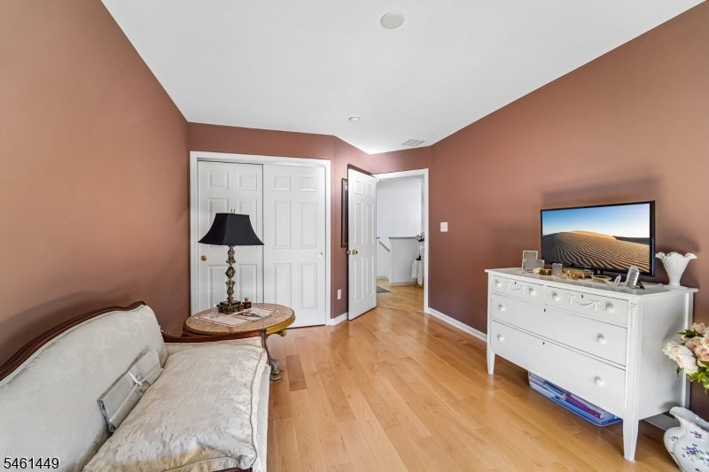 Bedroom with brown walls, hardwood floors, white dresser, and television.