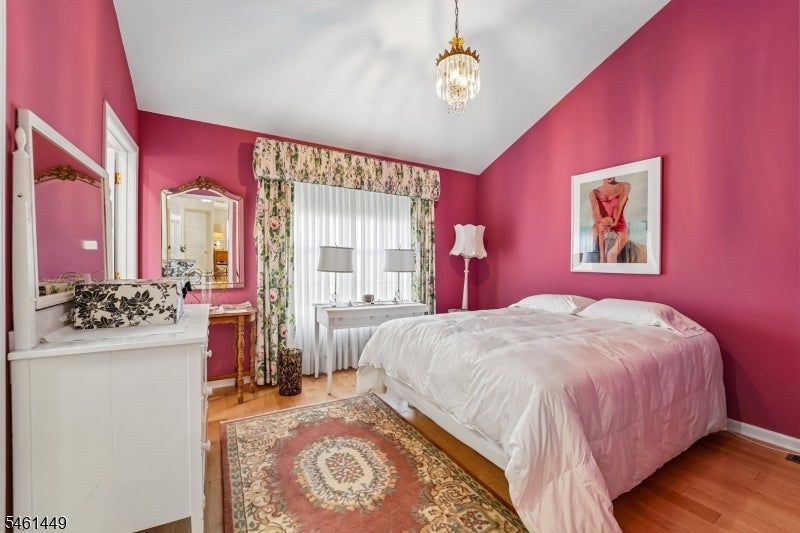 Bedroom with vivid pink walls, a white bed, floral curtains, and a patterned rug.