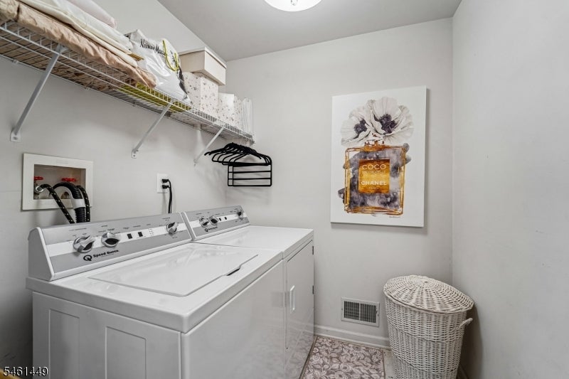 Laundry room with white washer and dryer, wire shelving, Coco Chanel print, and wicker hamper.