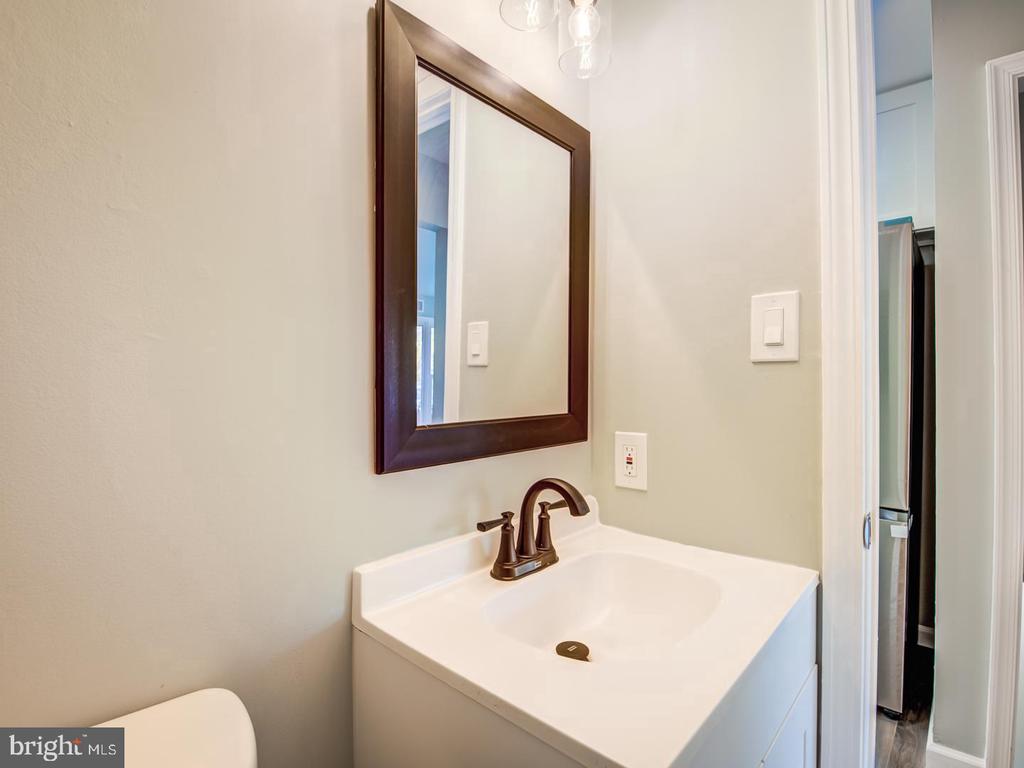 Bathroom vanity with a white sink, bronze faucet, and large dark-framed mirror.