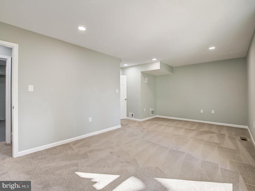 Finished basement room with beige carpet, gray walls, and recessed lights.