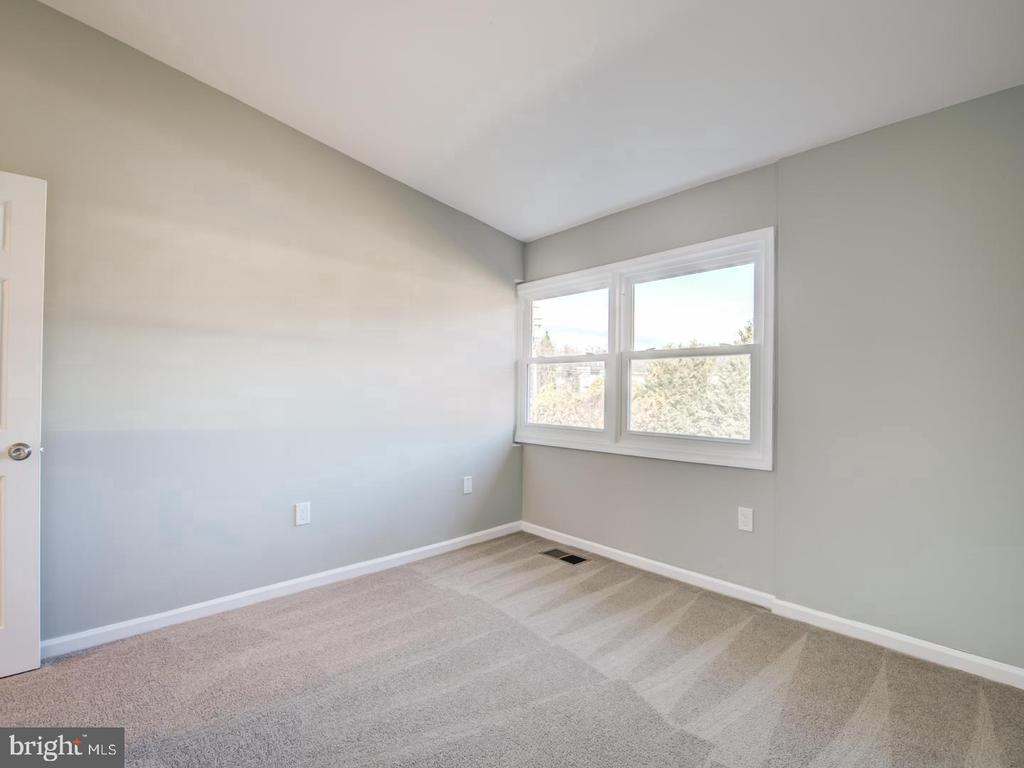 Empty bedroom with beige carpet, gray walls, and a large double window.