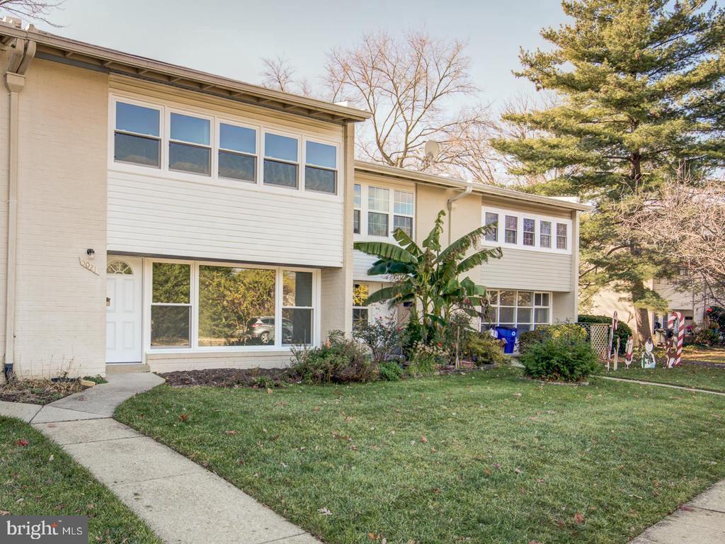 Attached two-story homes with light siding, a front lawn, and a walkway.