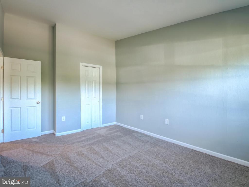 Empty carpeted room with gray walls and two white paneled doors.