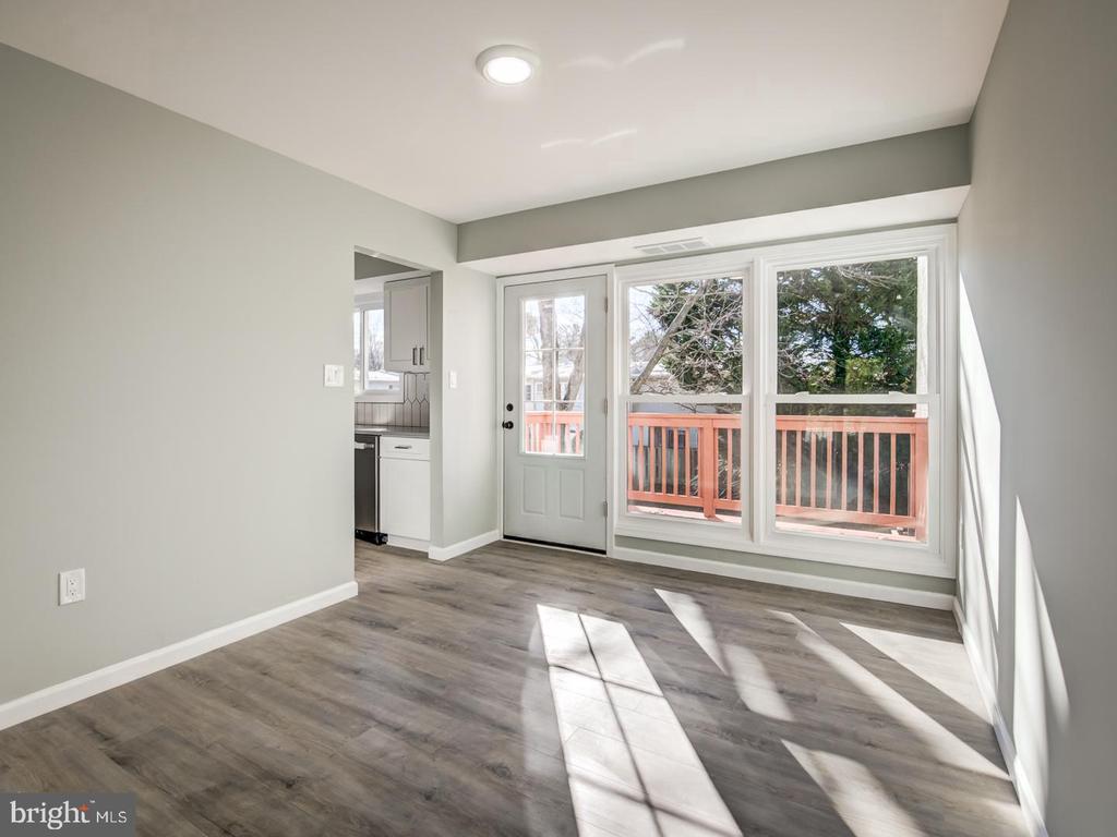 Vacant living area with gray flooring, large windows, and a glass door to a red-railed deck.