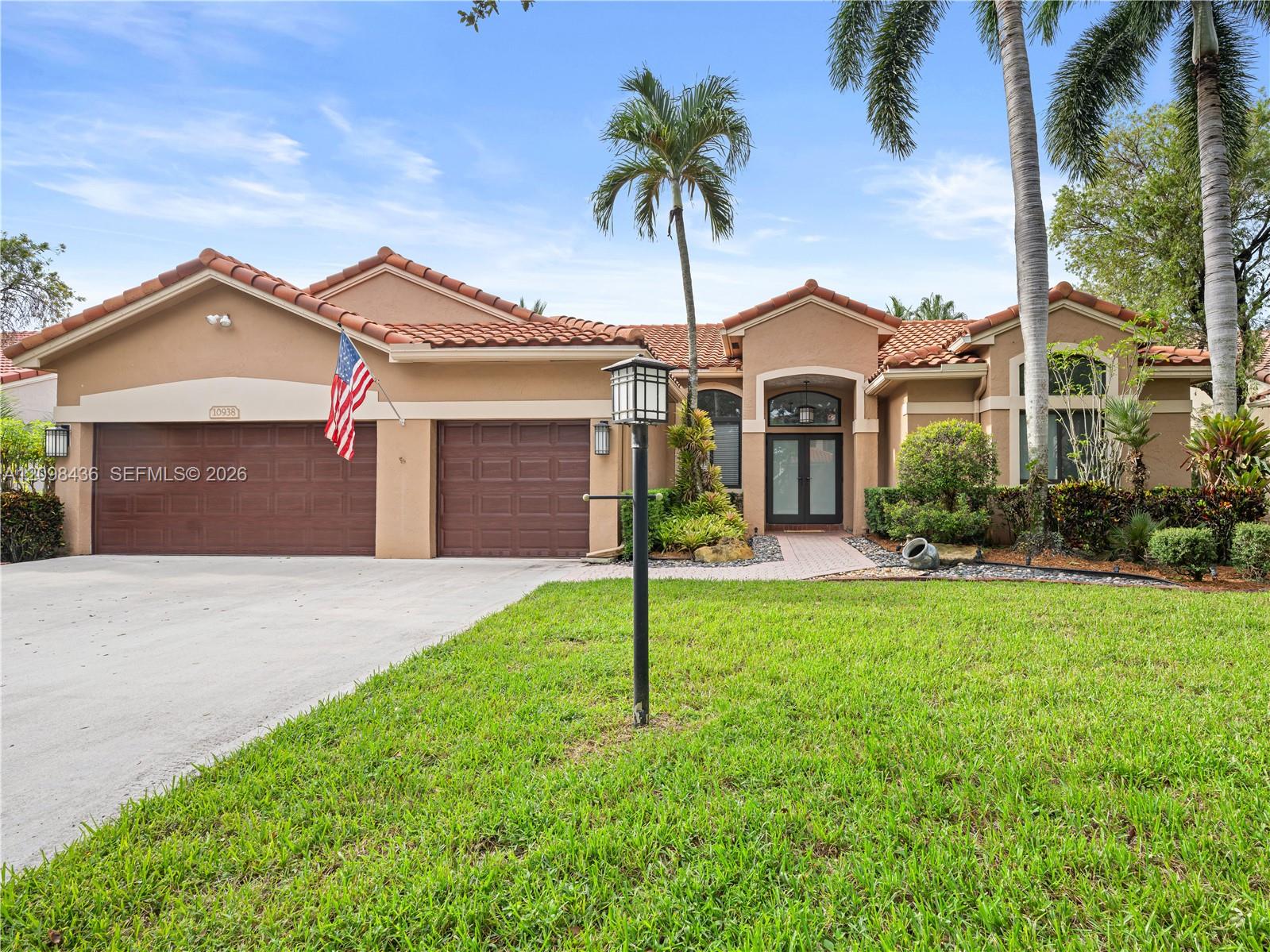 Stucco home with terracotta tile roof, double garage, palms, and a green front lawn.