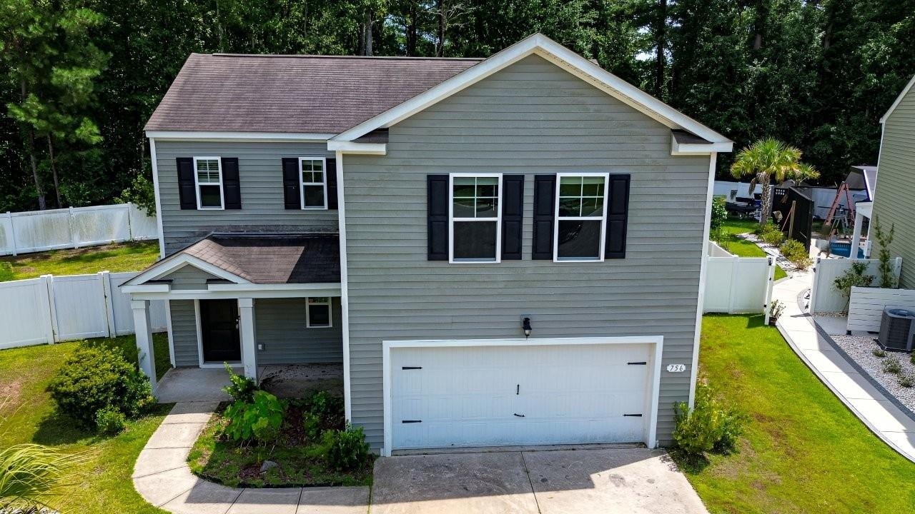 Gray two-story house with white garage door, black shutters, and curved walkway.
