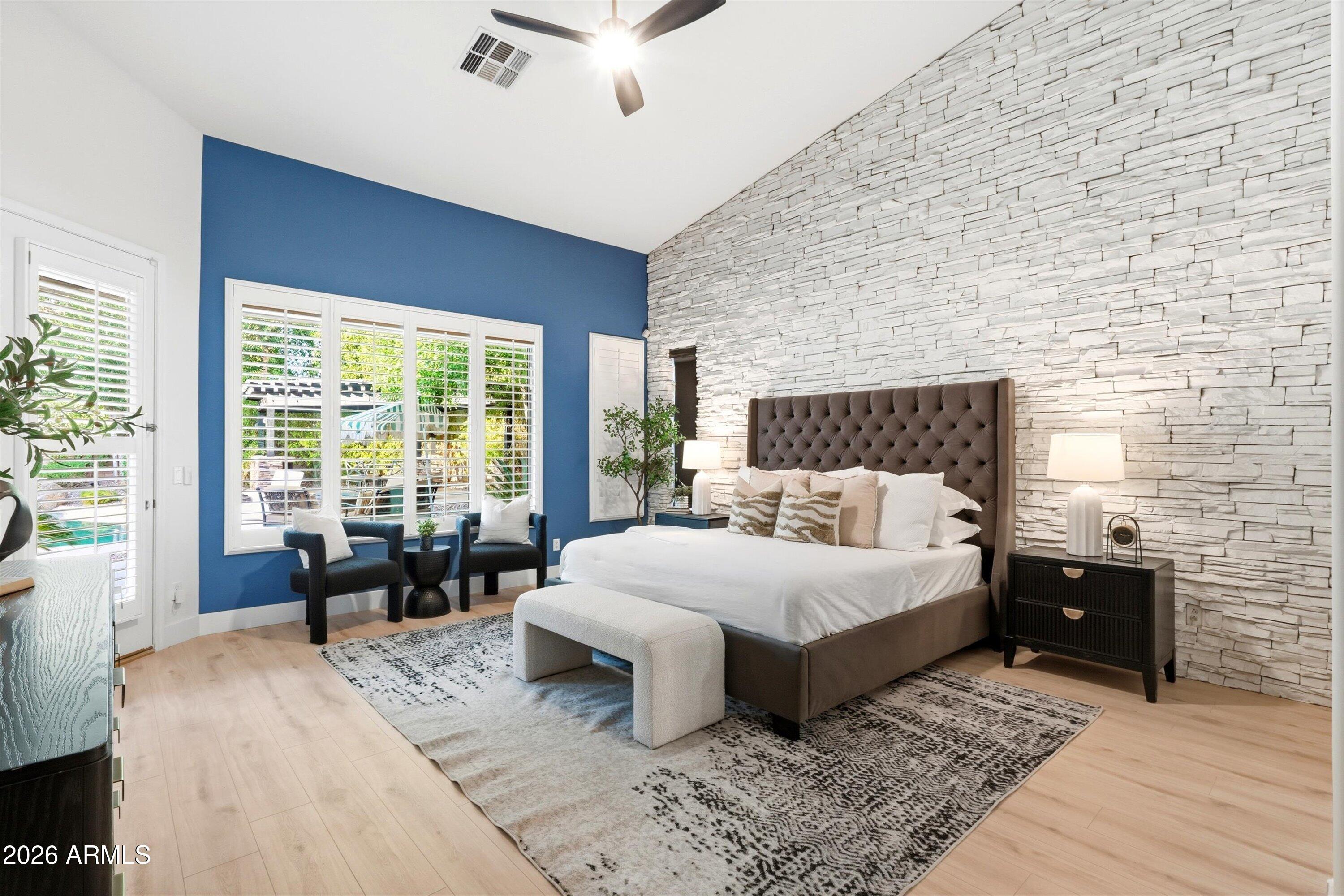 Bedroom with a white stone accent wall, blue window wall, and large upholstered bed.