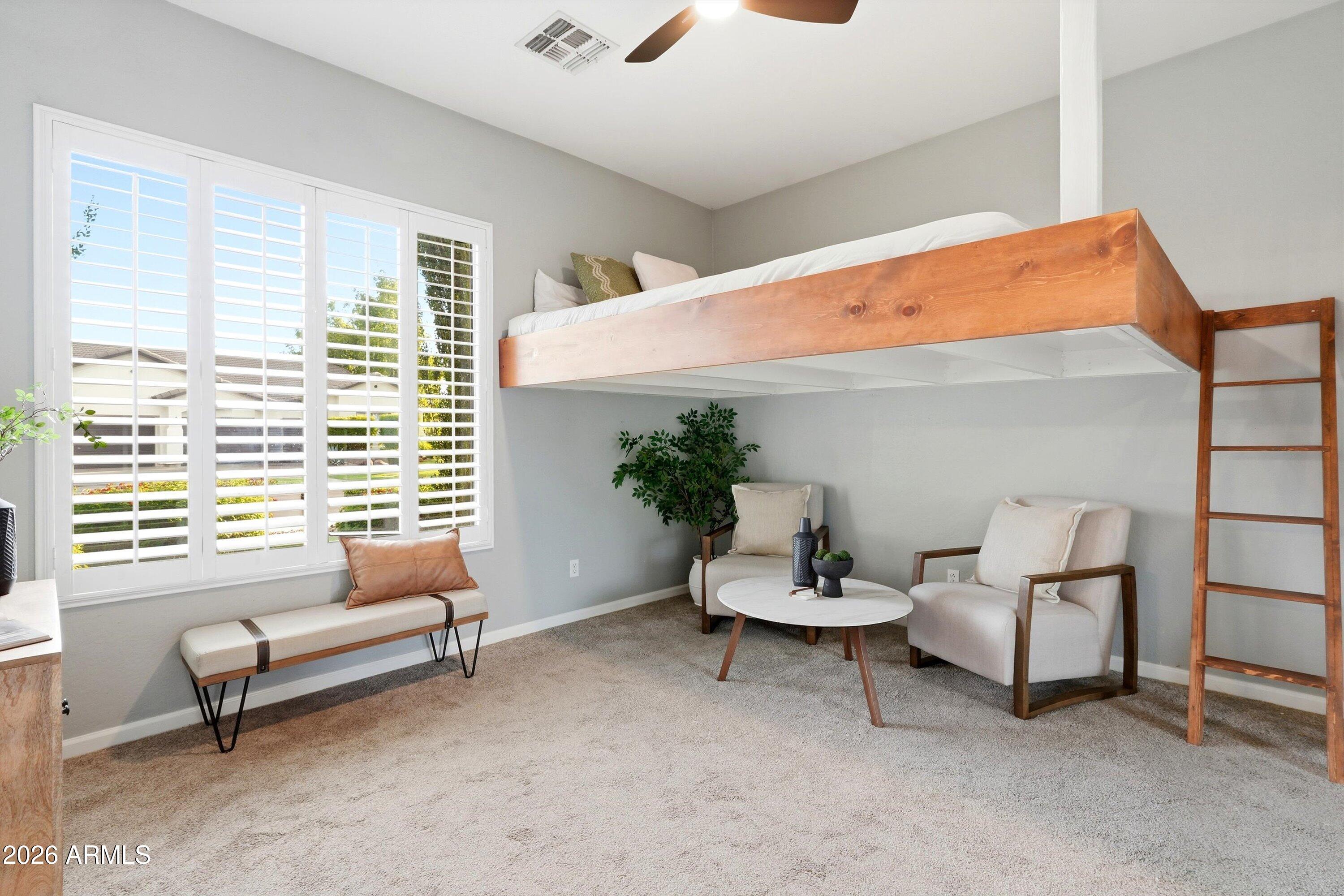 Bedroom with a raised wooden loft bed, ladder, and a cozy seating area by shuttered windows.