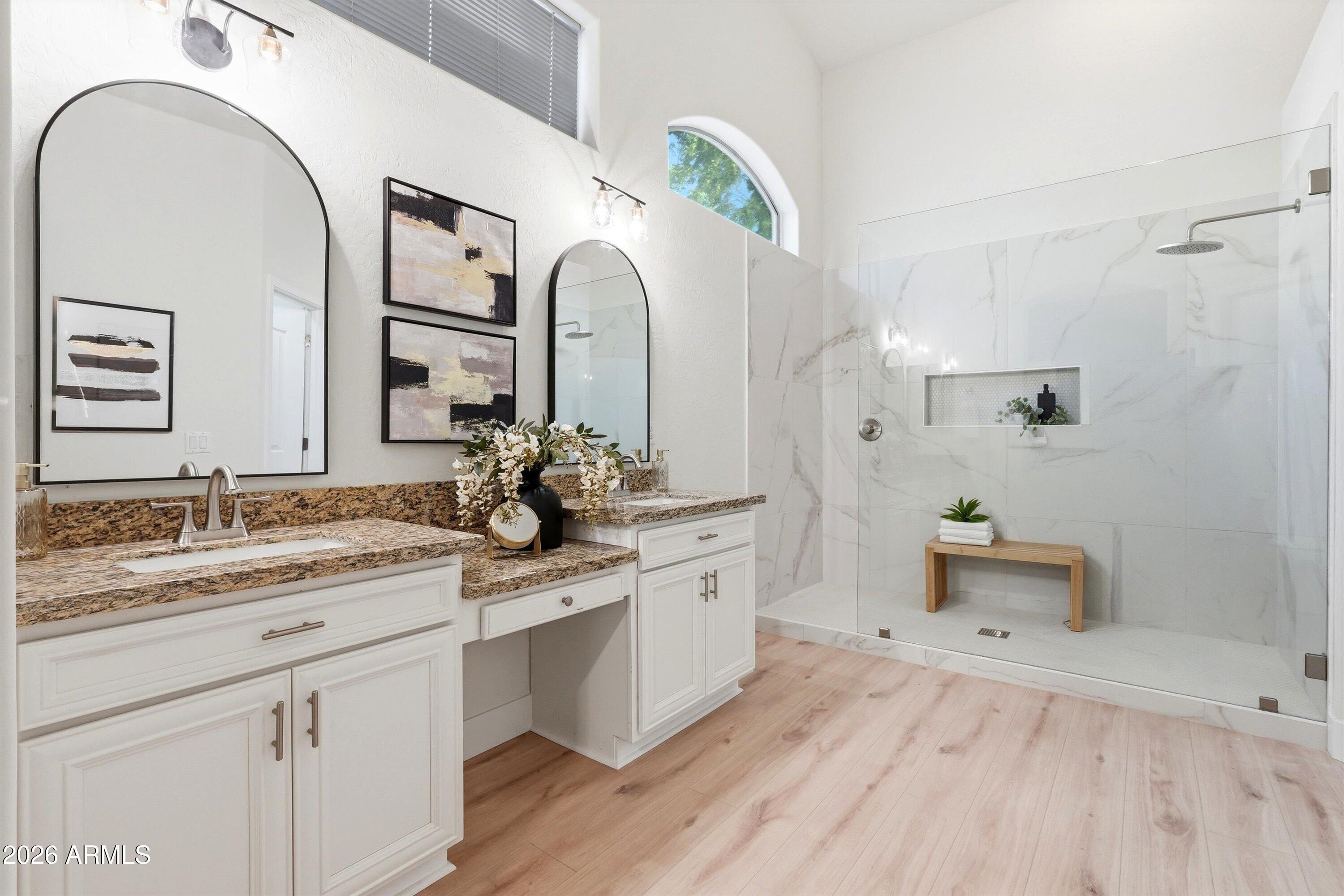 Bright bathroom with a double vanity and a spacious marble-look glass shower.