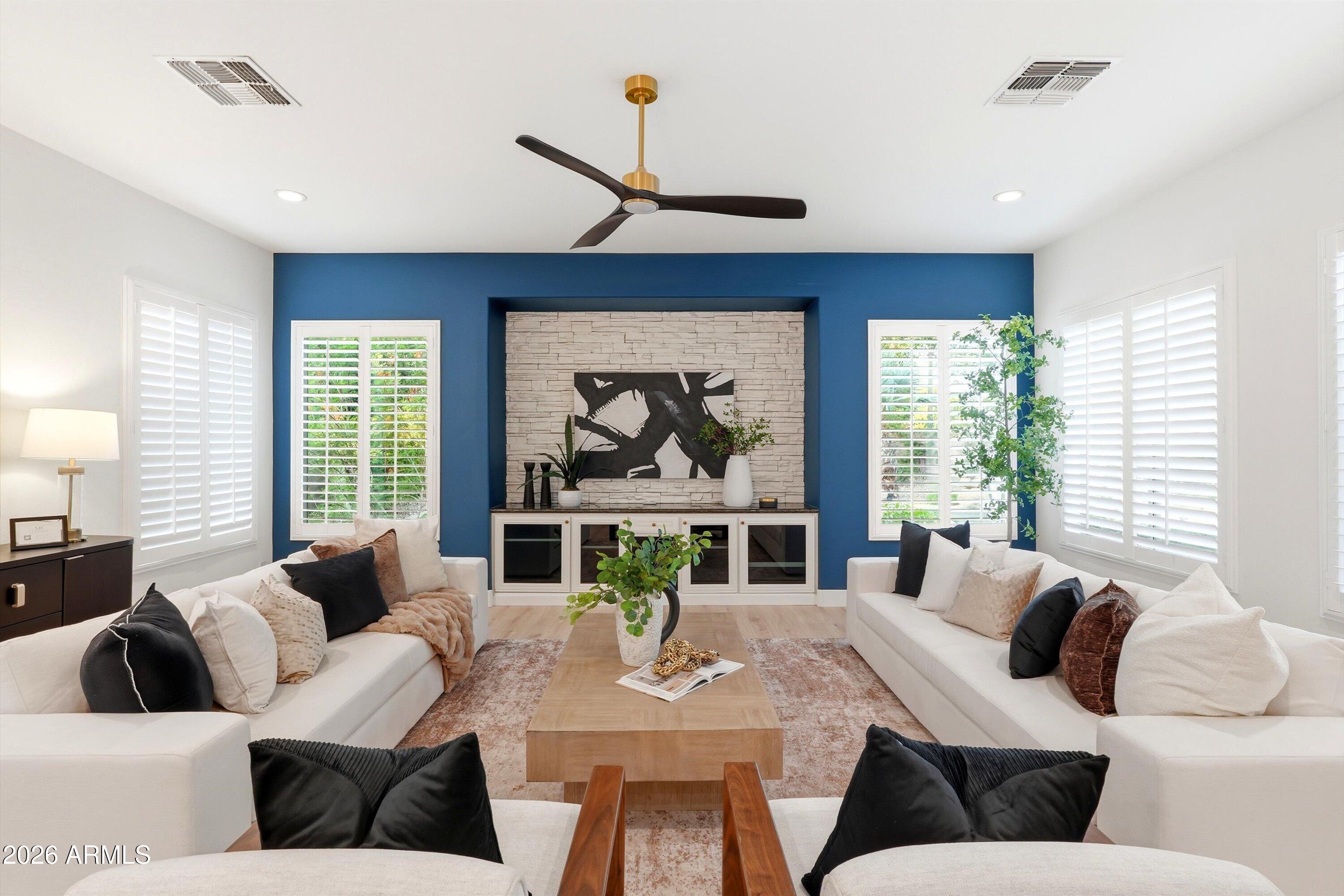 Living room with white sofas, a stone fireplace, and a deep blue accent wall.